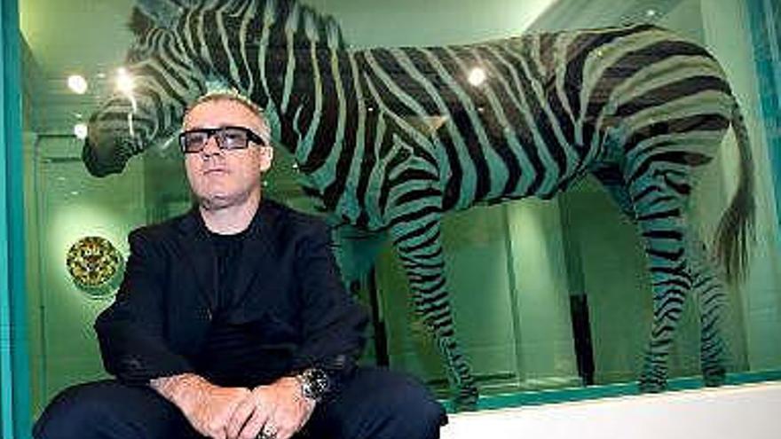 El artista británico Damien Hirst posa junto a su obra ´The Incredible Journey´ en la casa de subastas Sotheby´s en Londres, Reino Unido. Según lo previsto, la obra podría alcanzar la cifra de entre 2,5 y 3,8 millones de euros en la subasta que se celebrará el 15 y 16 de septiembre.