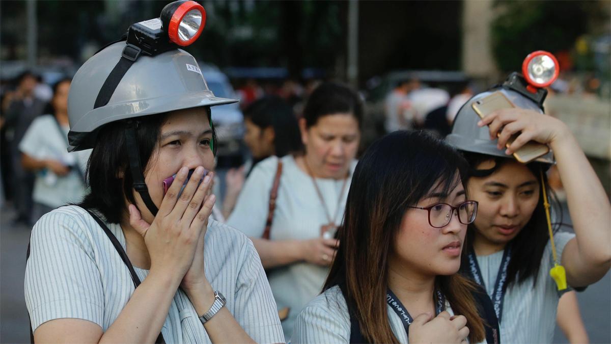 Trabajadores evacuados con casco de proteccion en las calles de Manila.