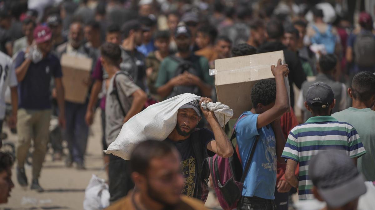Palestinos cargan cajas y bolsas con comida.