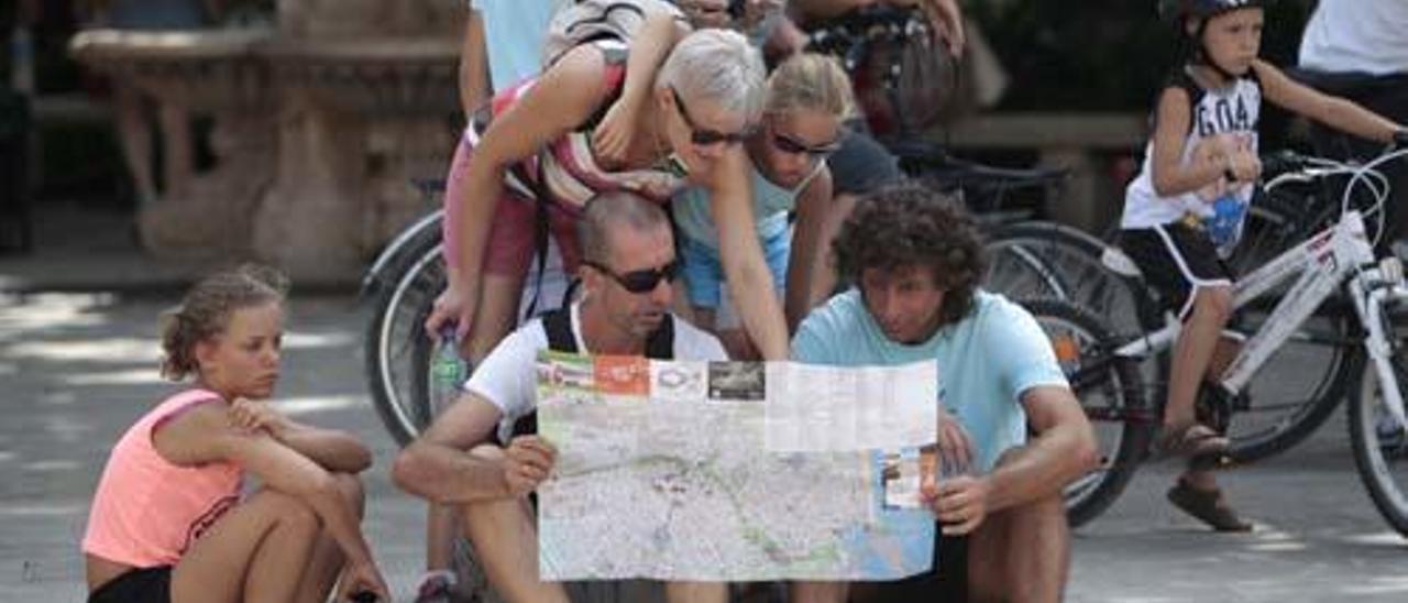 Una grupo de turistas consulta un plano de Valencia en la Plaza de la Virgen.