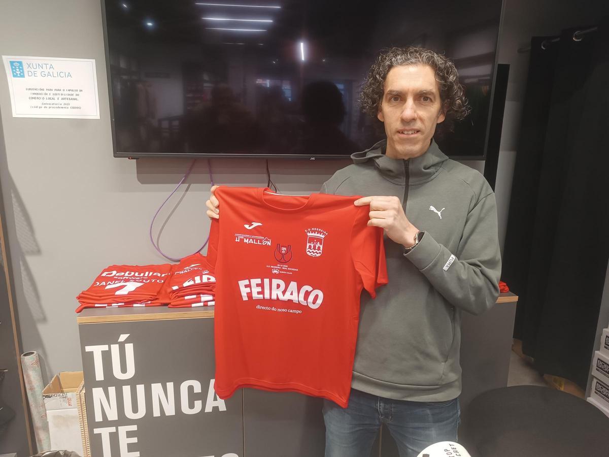 Alberto García muestra una de las camisetas del Negreira que comercializa en