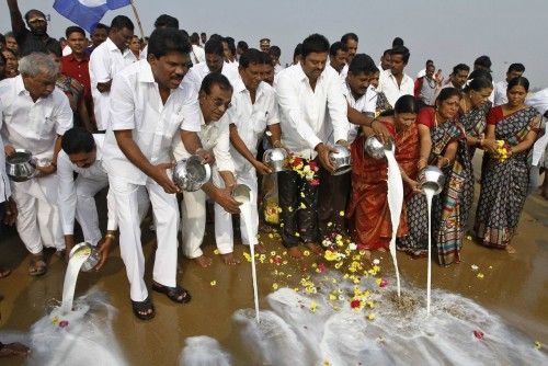 People pour milk into the Bay of Bengal as a gesture of respect to the victims of the 2004 tsunami during the ninth anniversary of the disaster, at Marina beach in Chennai