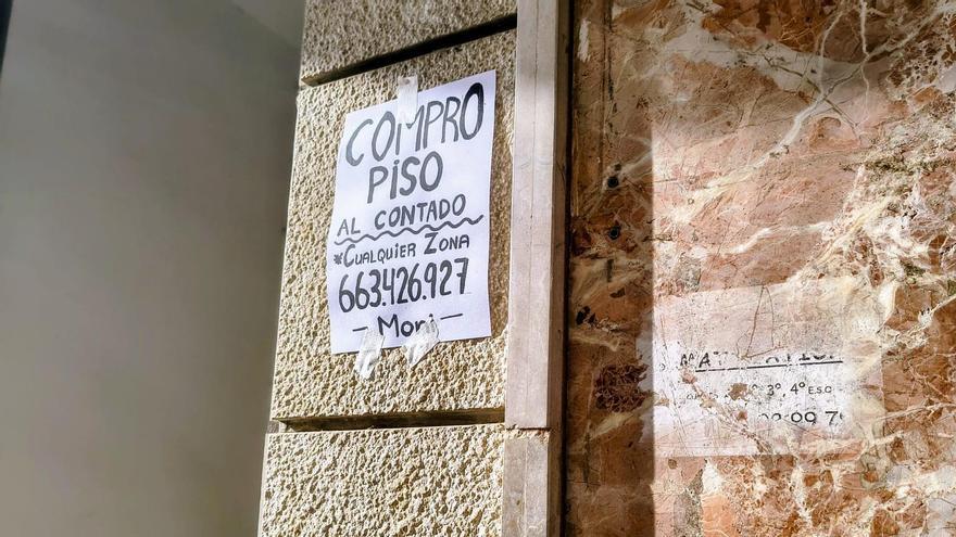 Cartel de "Compro piso" pegado de forma reciente en una fachada de la calle Cerdán de Tallada de Xàtiva.