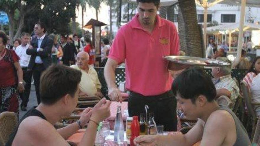 Un camarero atiende a los clientes de una terraza.