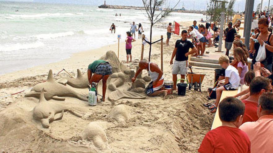 Unos hombres levantan una espectacular figura de arena en la playa de Can Picafort.