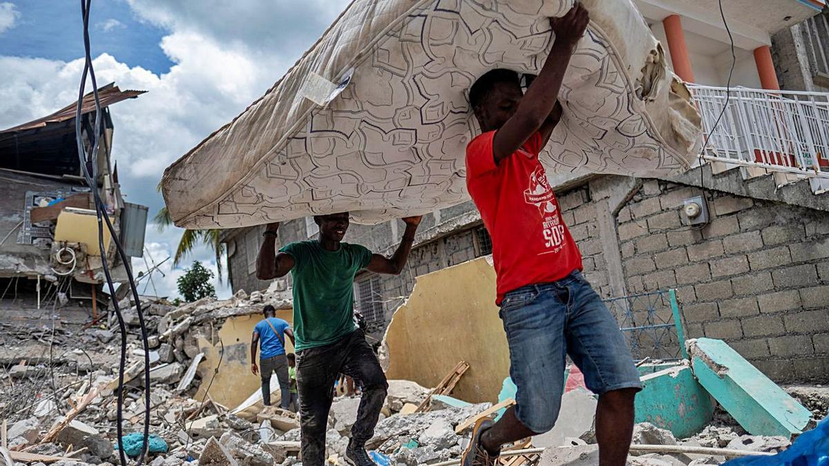 Dos nois porten un matalàs d’un hotel destrossat a Los Cayos, Haití. | REUTERS