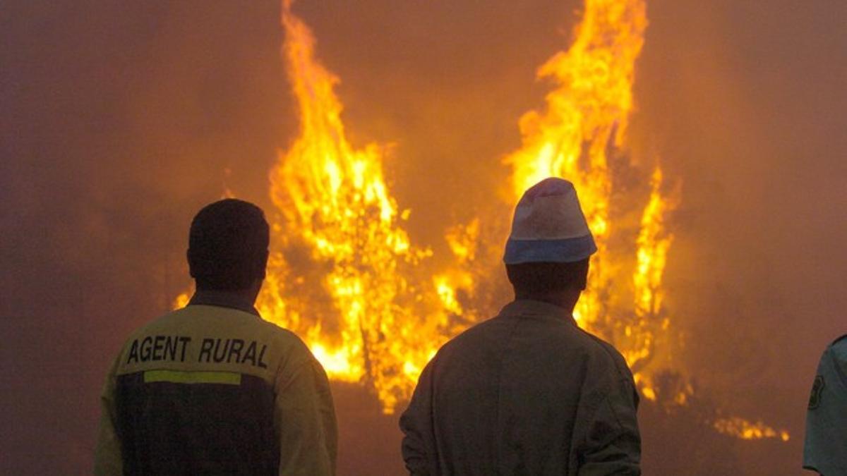 Un agente rural y un vecino vigilan que las llamas no se acerquen a las granjas durante un incendio, en mayo del 2005.