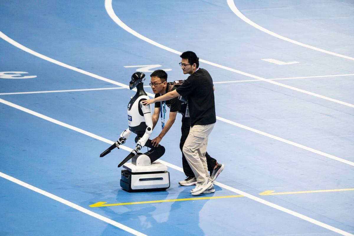 Técnicos empujan un robot humanoide a través de una pista de carreras durante los Juegos Mundiales de Robots Humanoides en Pekín, China, el viernes 15 de agosto de 2025. El evento se celebra hasta el 17 de agosto. Fotógrafo: Qilai Shen/Bloomberg