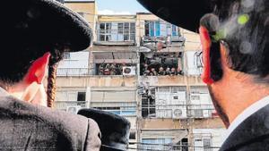 Jueus ultraortodoxos observen els militars israelians durant la inspecció de l’edifici bombardejat per l’Exèrcit de l’Iran al barri residencial Bnei Brak, a Tel-Aviv, ahir.