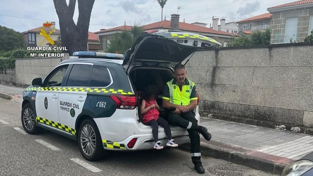 La niña localizada sola en Nigrán junto al guardia civil en el coche patrulla.