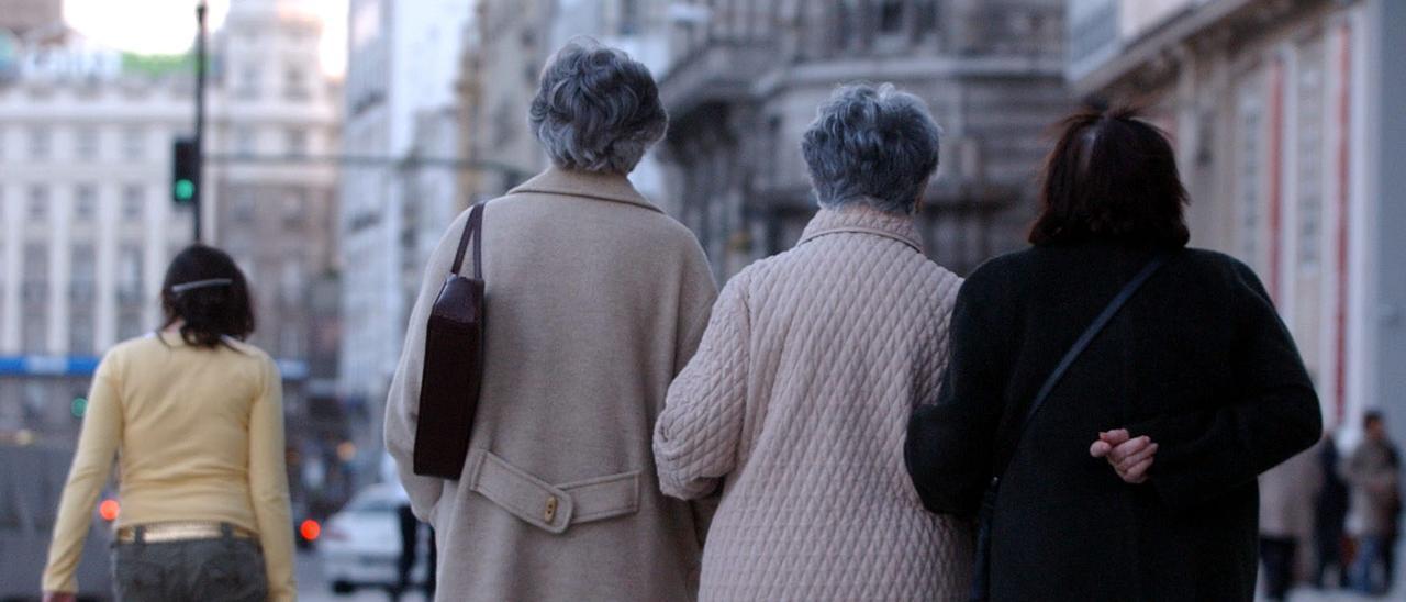Tres mujeres mayores, paseando por la calle de una ciudad.