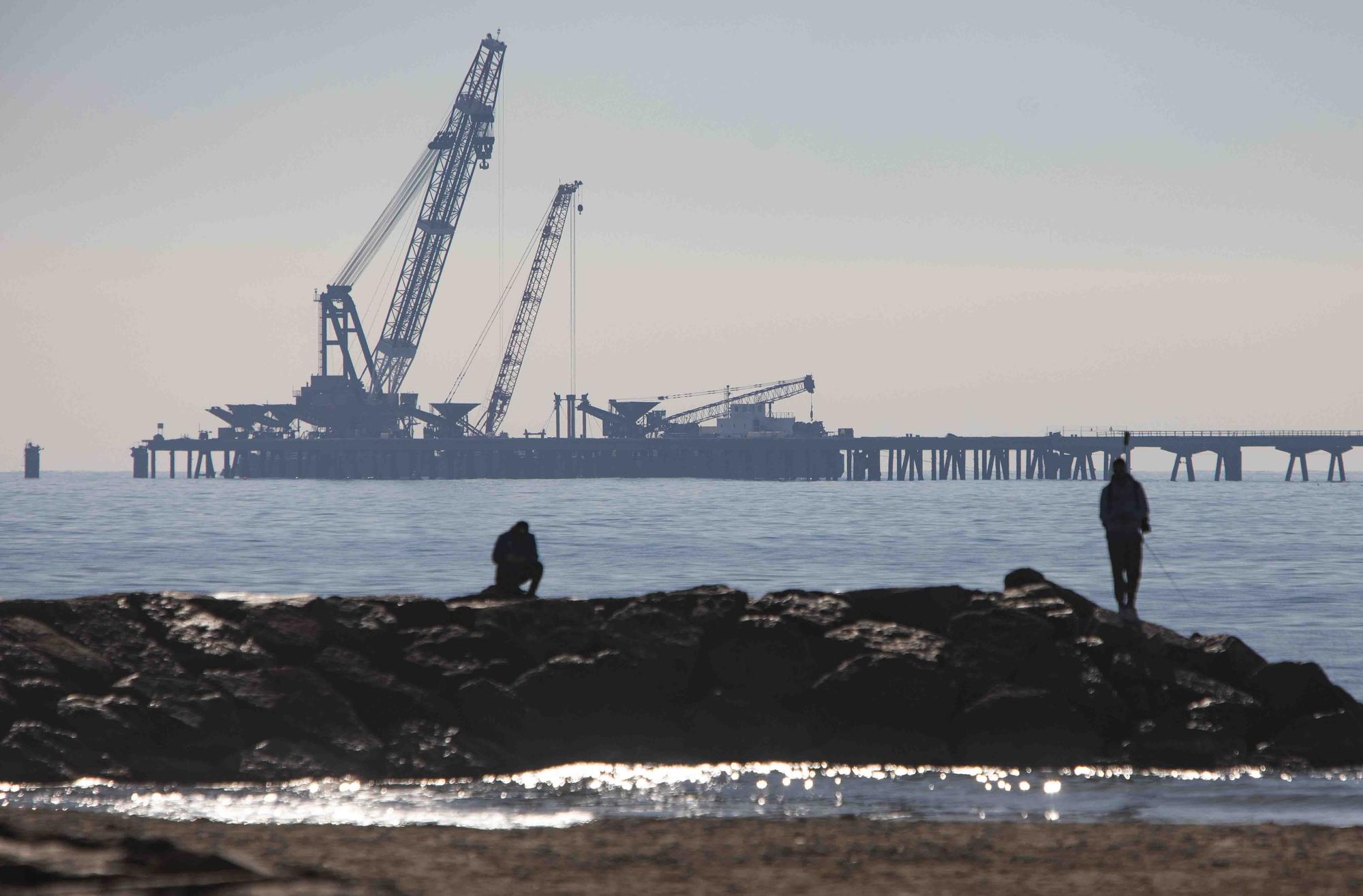 Vecinos del Port de Sagunt observan desde la playa la retirada de las tolvas del Pantalán