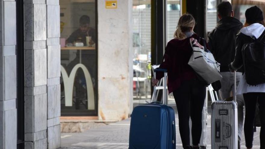 Turistas arrastran maletas en una calle de Ibiza.