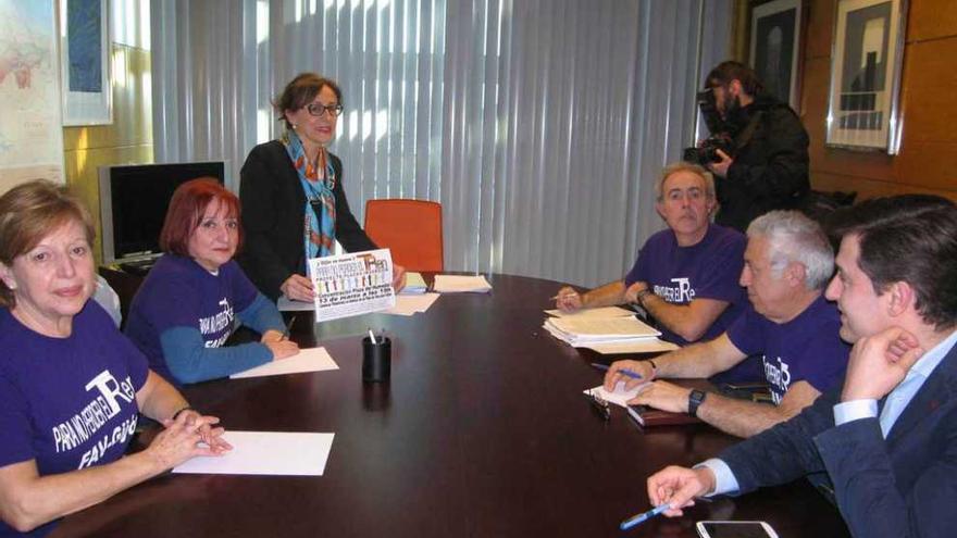 Belén Fernández, al fondo, posa con el cartel anunciador de la movilización del viernes en su reunión con representantes vecinales de la plataforma en defensa del plan de vías y el diputado socialista José María Pérez.