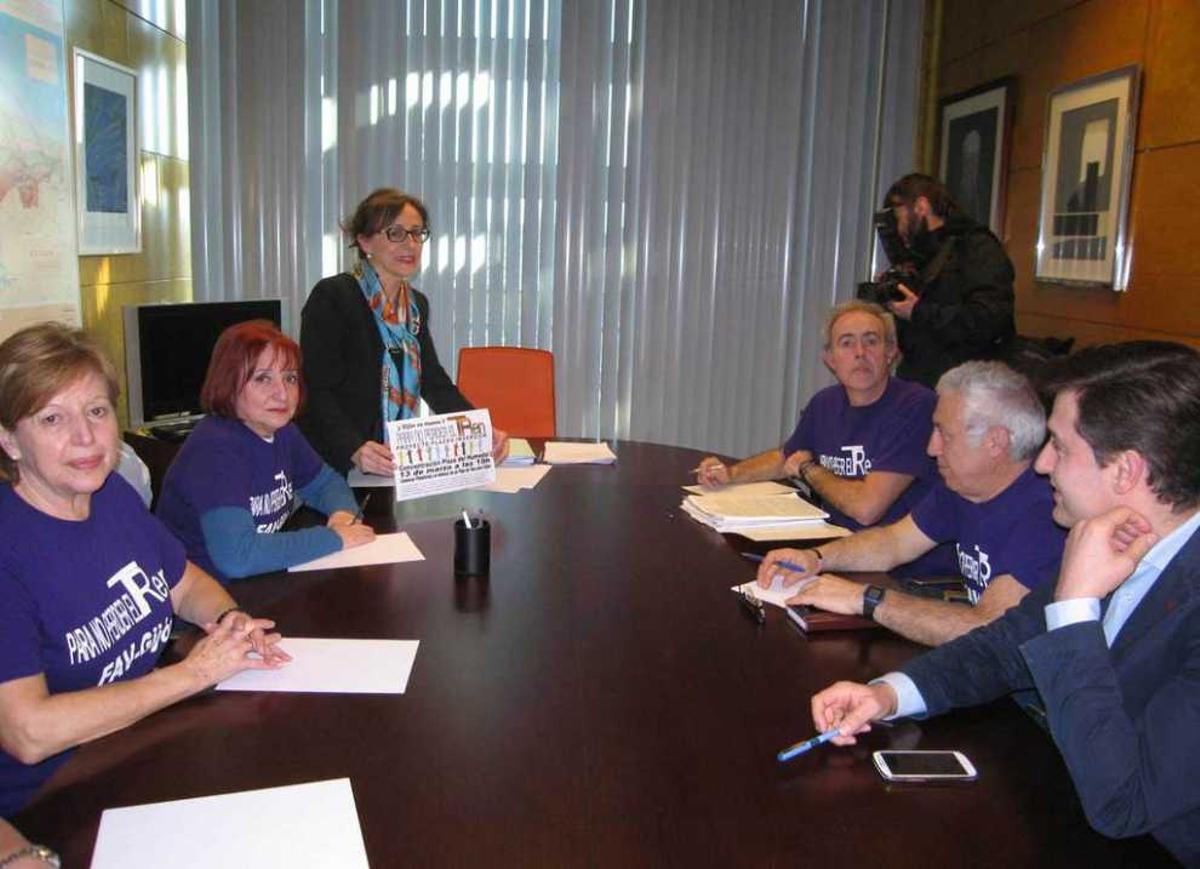 Belén Fernández, al fondo, posa con el cartel anunciador de la movilización del viernes en su reunión con representantes vecinales de la plataforma en defensa del plan de vías y el diputado socialista José María Pérez.