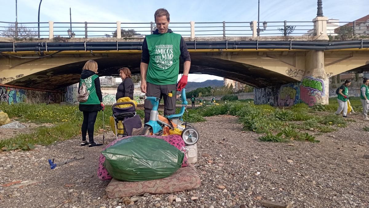 Un voluntario de Andalimpia, con algunos de los restos retirados del cauce del Guadalmedina.