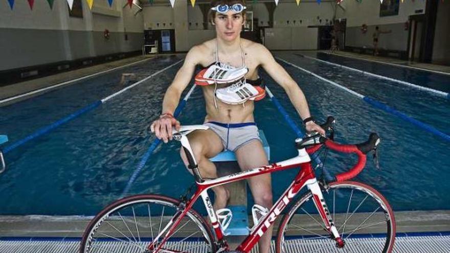 El triatleta posa en la piscina de la UA con su bicicleta y zapatillas de correr.