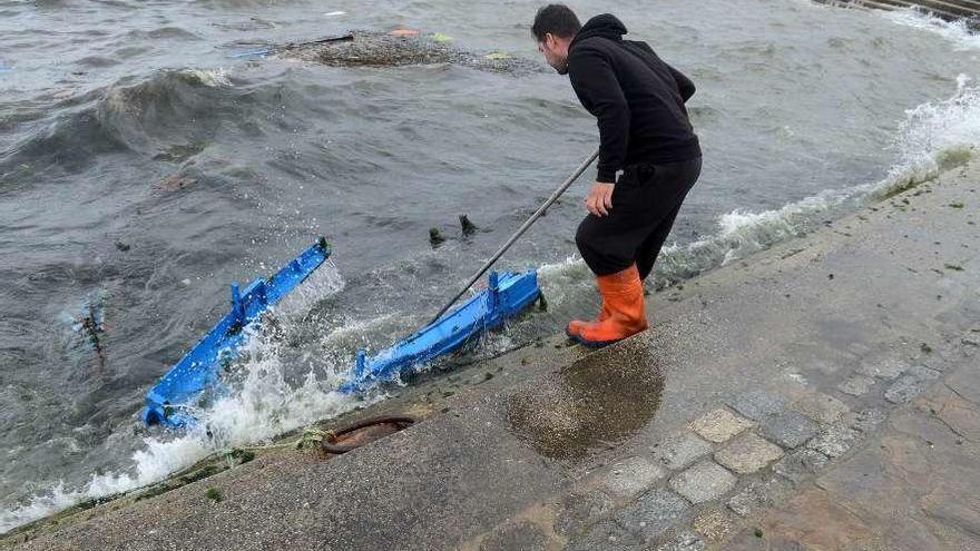 Un marinero observa los restos de una dorna que se deshizo contra el paseo marítimo de A Illa. // N. P.