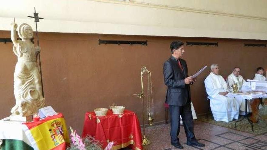 Alejandro Albarrán explica la talla de San Juan Bautista. Centro, asistentes a la celebración religiosa. A la derecha, el sacerdote procede a la bendición de la talla .