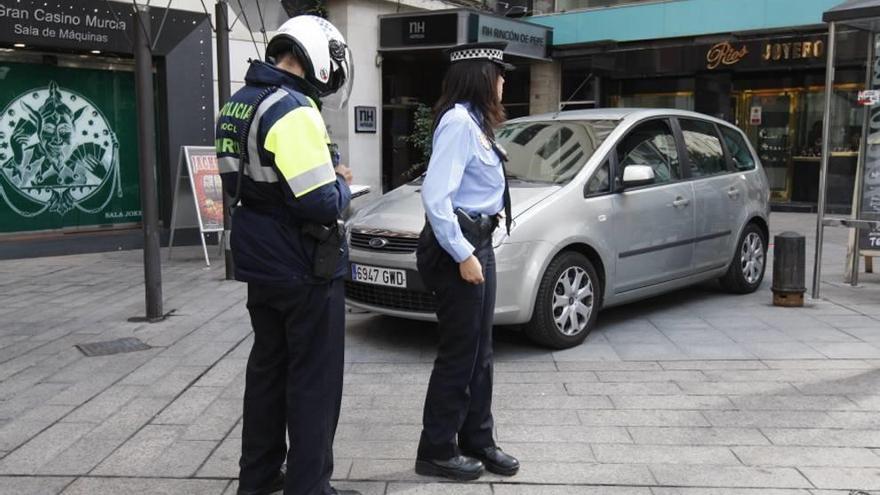 Un agente pone una sanción a un vehículo mal aparcado.