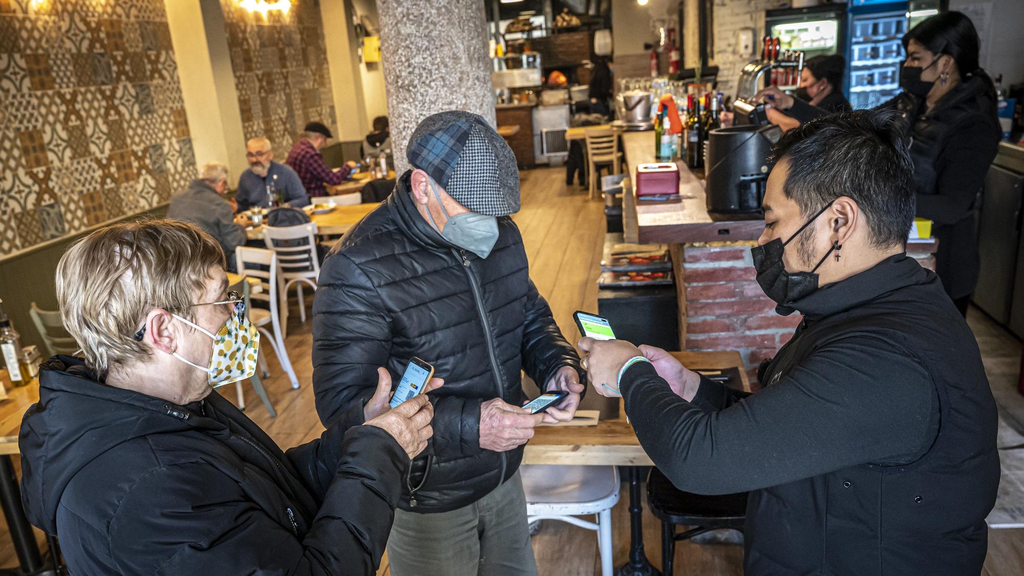 Unos clientes enseñan el pasaporte covid en un restaurante de Barcelona.