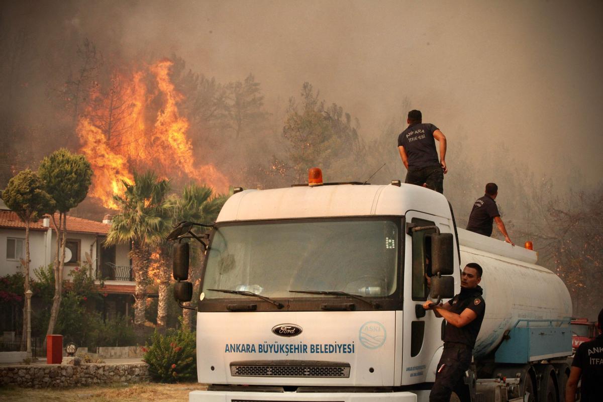 Bomberos trabajan en la extinción del incendio que se extiende por la ciudad costera de Oren, en Turquía.