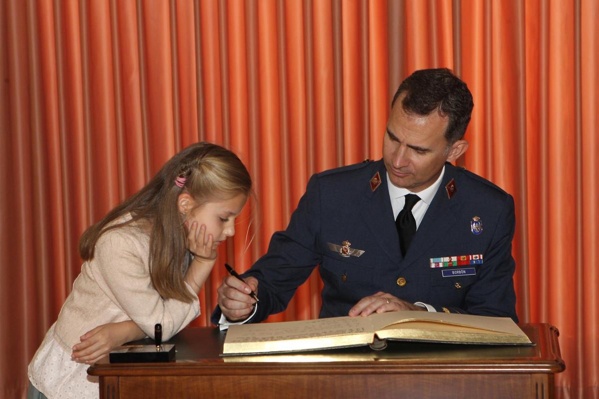 Leonor mira cómo su padre escribe en el libro de honor de la Base Aérea de San Javier (Murcia), en mayo de 2014, un mes antes de que Juan Carlos I abdicara.