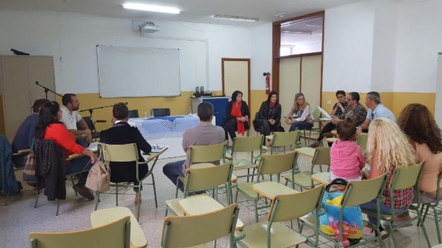 La consejera regional Soledad Monzón, al fondo, durante la reunión con los padres, ayer.