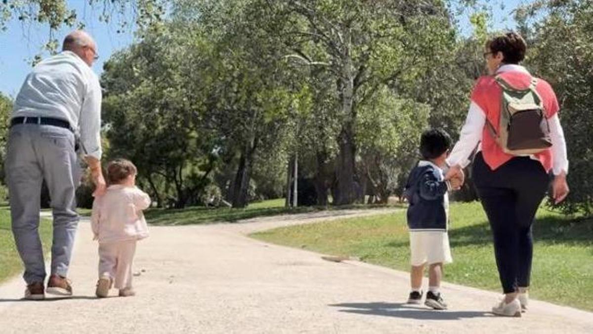 Rosa María Paricio y Jesús Navarro pasean por un parque junto a dos menores acogidos por su familia.