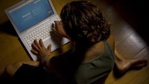 Una mujer escribe en el teclado de su ordenador.
