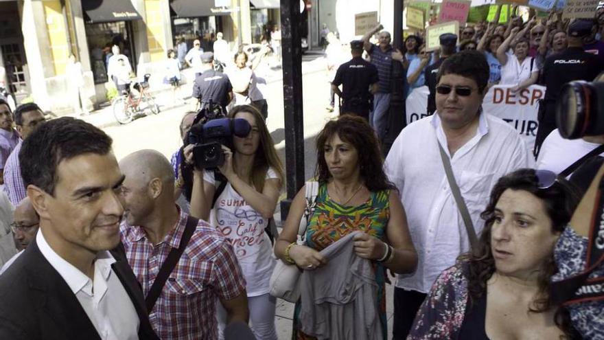 Pedro Sánchez, a la puerta del Centro de Cultura Antiguo Instituto Jovellanos de Gijón, con la protesta de los trabajadores de Liberbank al fondo, antes del inicio de la jornada organizada por UGT.