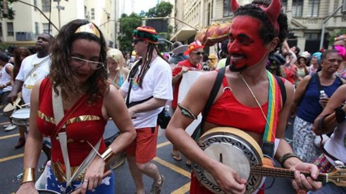 Dos componentes de una de las comparsas más madrugadoras del Carnaval desfilan por el centro de Río, el domingo.