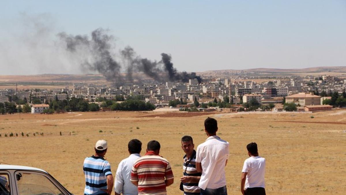 Gente mira el humo de los combates en Kobane desde la frontera turca.