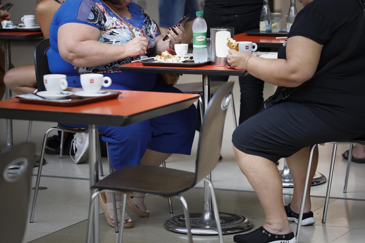 Dos personas obesas consumen en una terraza.