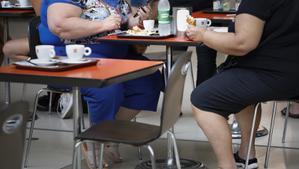 Dos personas obesas consumen en una terraza.