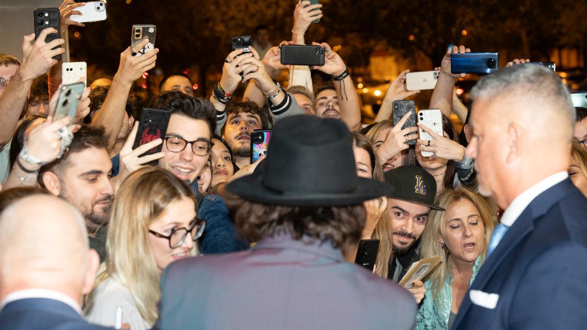 El actor y director Johnny Depp saludan a los fans durante su paso por la alfombra roja