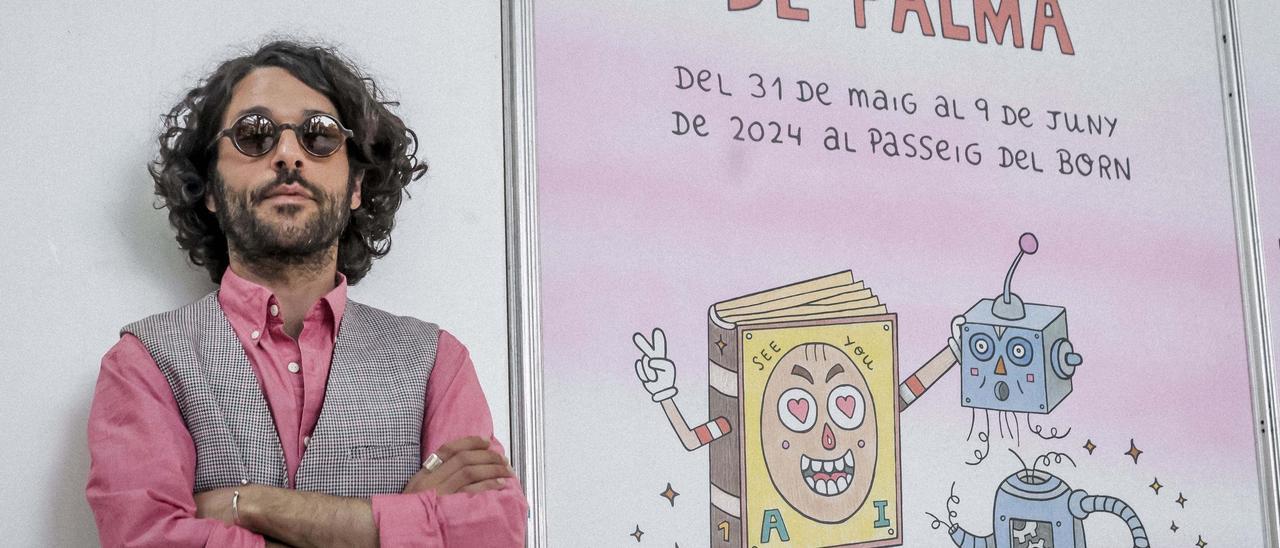 El artista Albert Pinya posa junto al cartel que realizó para la pasada Fira del Llibre