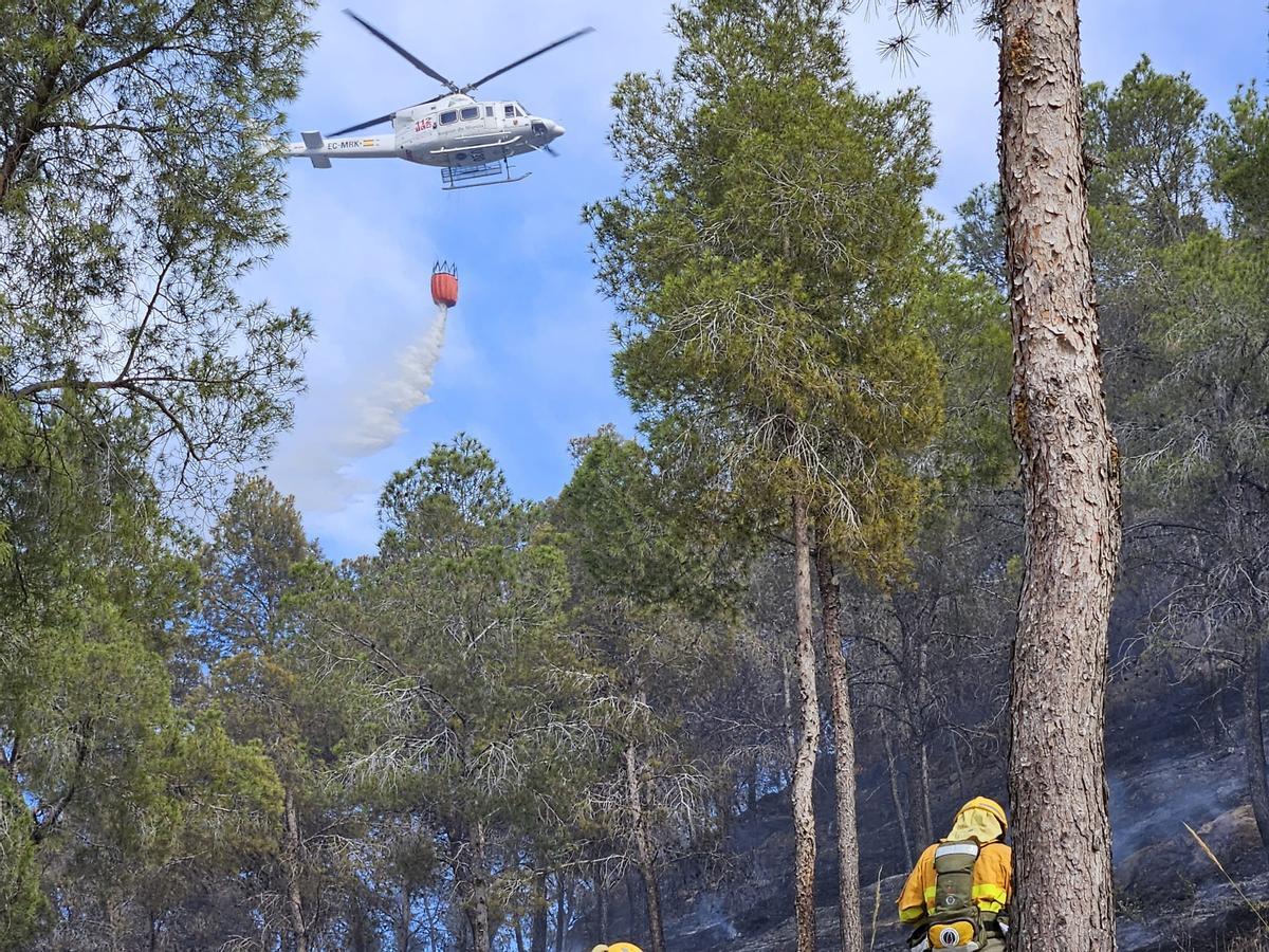 Uno de los helicópteros suelta la carga de agua sobre las llamas del incendio en la Cresta del Gallo, en Murcia.
