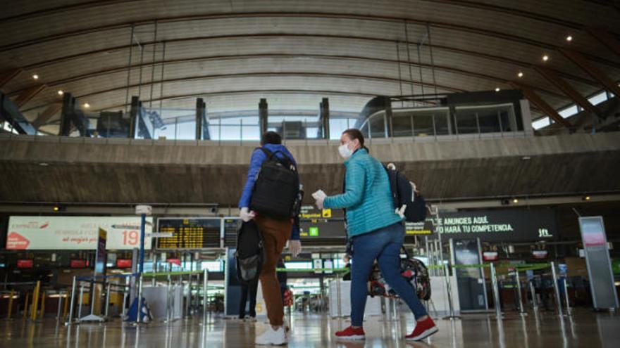 Dos pasajeros se dirigen a embarcar en un aeropuerto de Los Rodeos vacío por la epidemia.