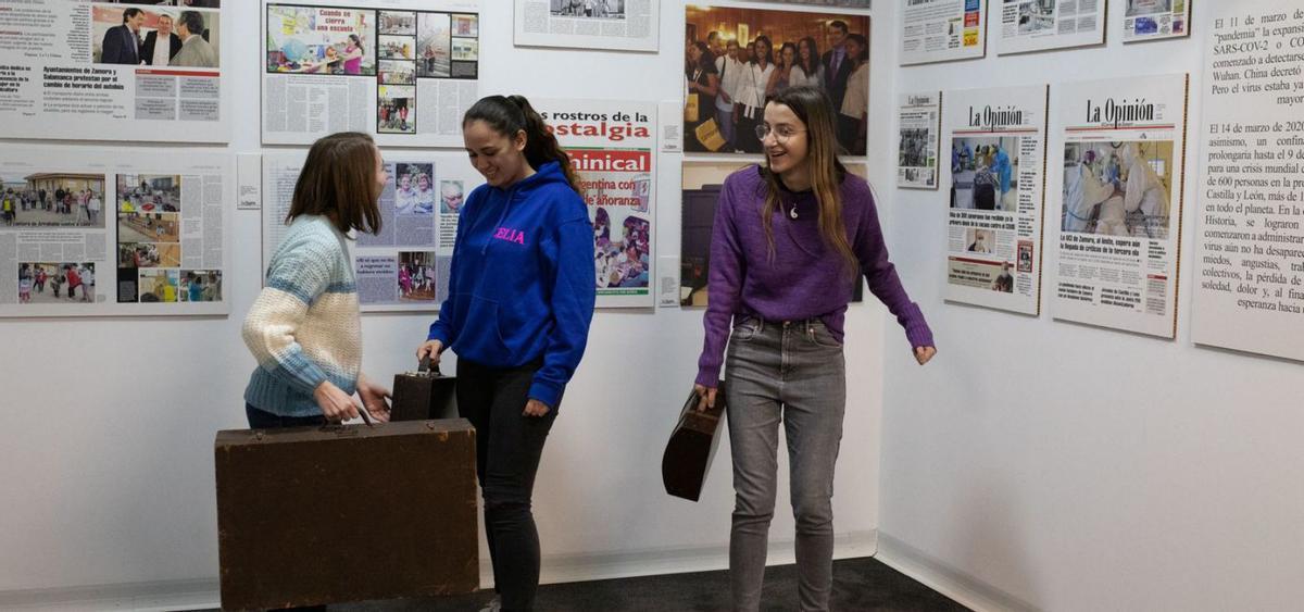 Varias estudiantes con maletas antiguas frente a la muestra de portadas destacadas del diario. | Ana Burrieza