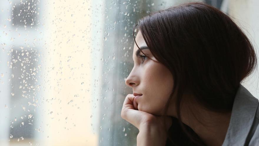 Una mujer mira por la ventana de su casa.