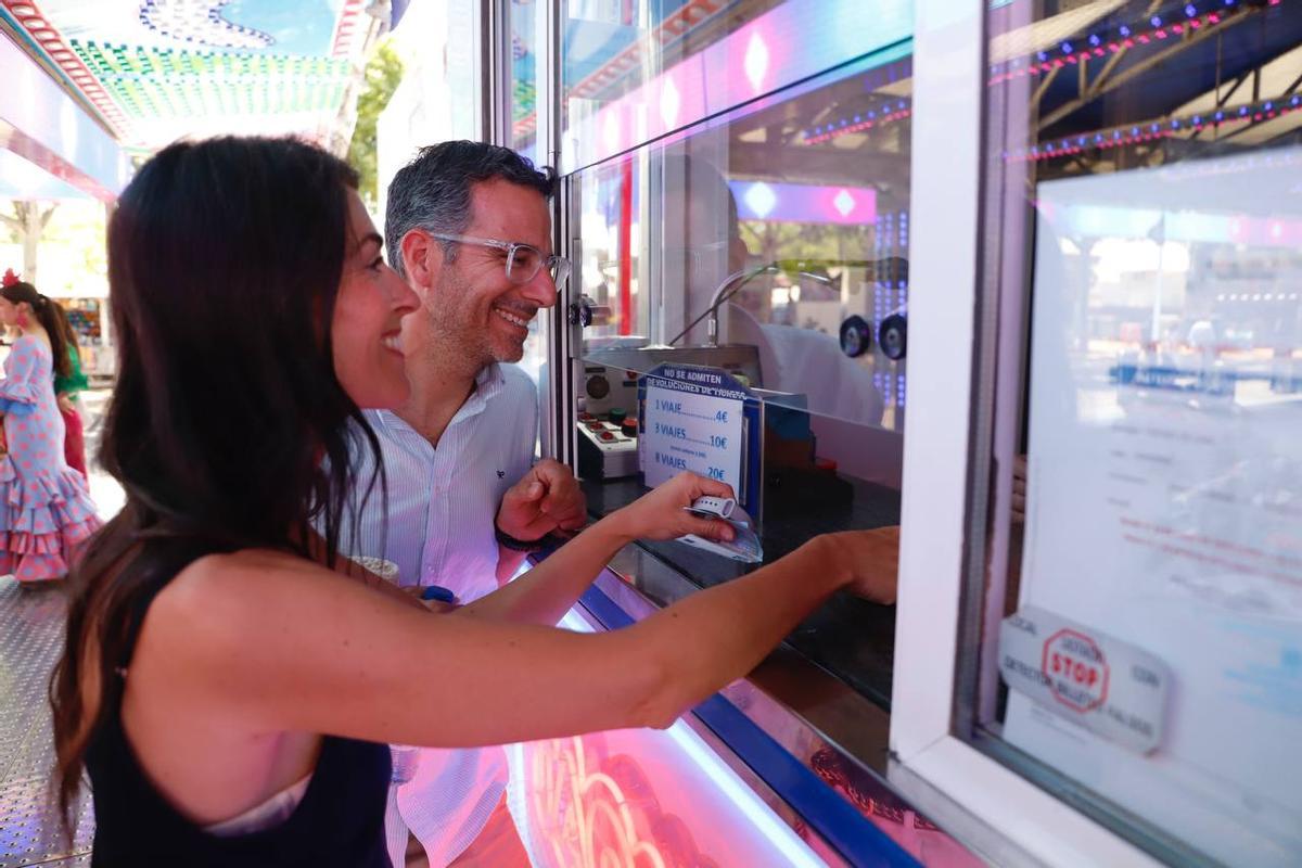 Dos personas compran tickets en una de las atracciones de la Feria de Córdoba.