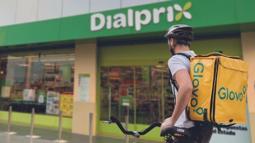 Repartidor de Glovo a las puertas de un supermercado para recoger un pedido de compra online.