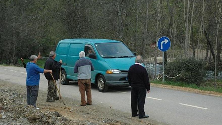 Un vehículo pasa por la carretera fronteriza de Aliste con Portugal ante la presencia de varios vecinos.