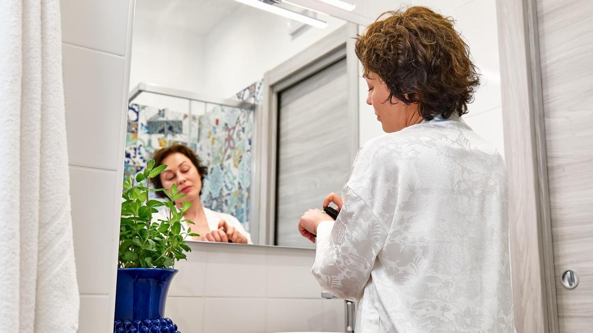 Una mujer se aplica un producto de belleza.