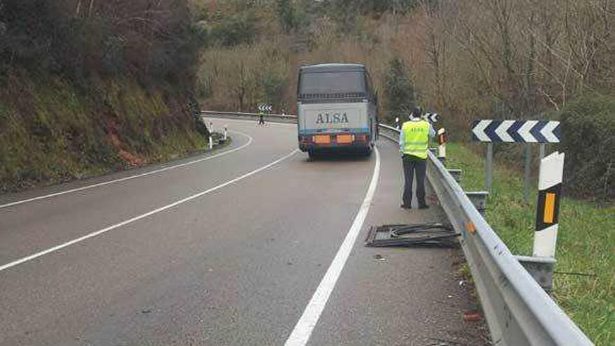 El autobús accidentado, con restos del choque sobre la vía.