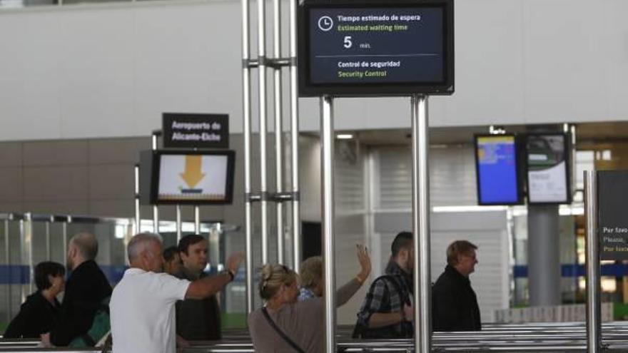 Pasajeros accediendo a la sala de embarque. Un monitor informa del tiempo para pasar el control.