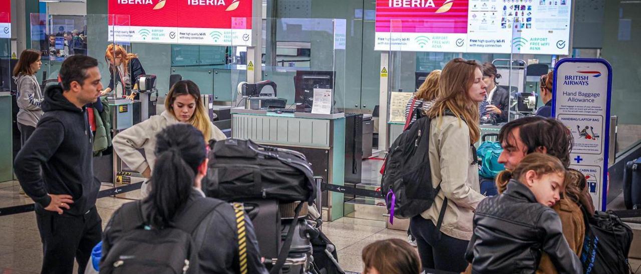 Viajeros esperan facturar sus maletas ante un mostrador de Iberia, en el aeropuerto de El Prat, en Barcelona.