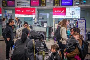 Viajeros esperan facturar sus maletas ante un mostrador de Iberia, en el aeropuerto de El Prat, en Barcelona.