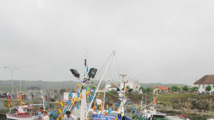 A la izquierda, &quot;El Reviru&quot; con la imagen de Santa Ana ya a bordo y, sobre estas líneas, la procesión.